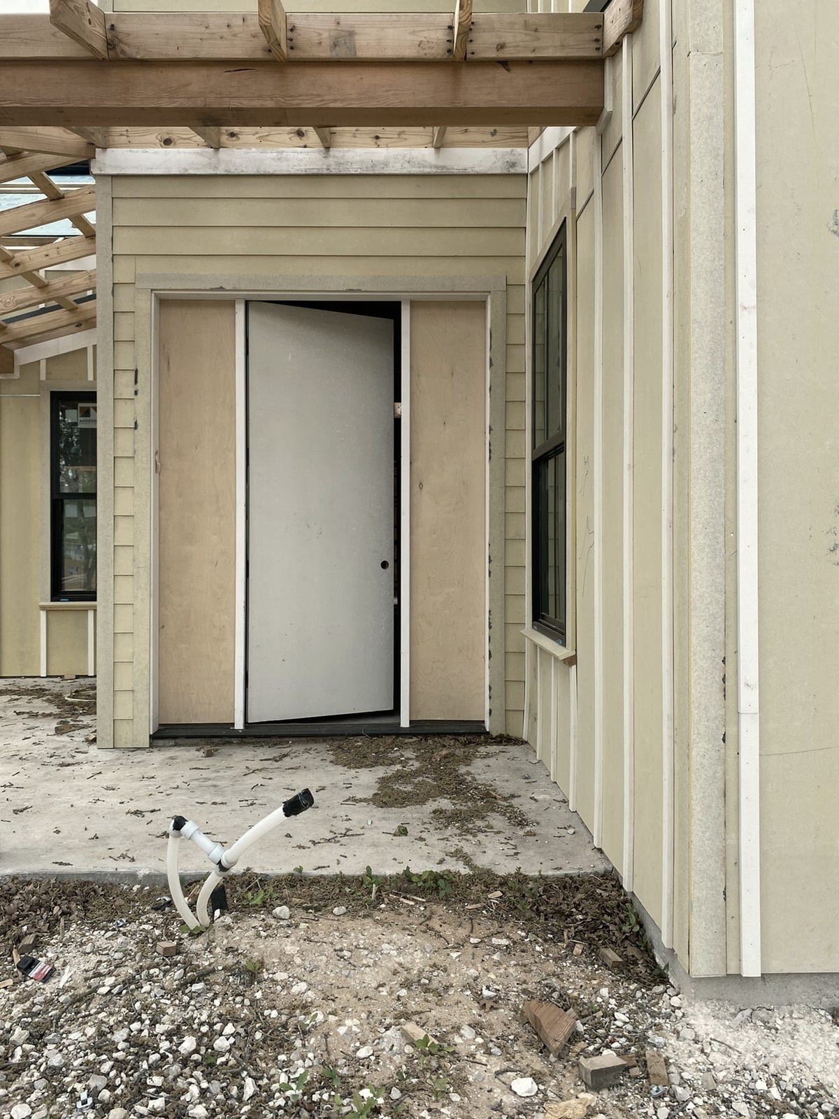 A house under construction with a white pipe stub-out at the edge of the slab.